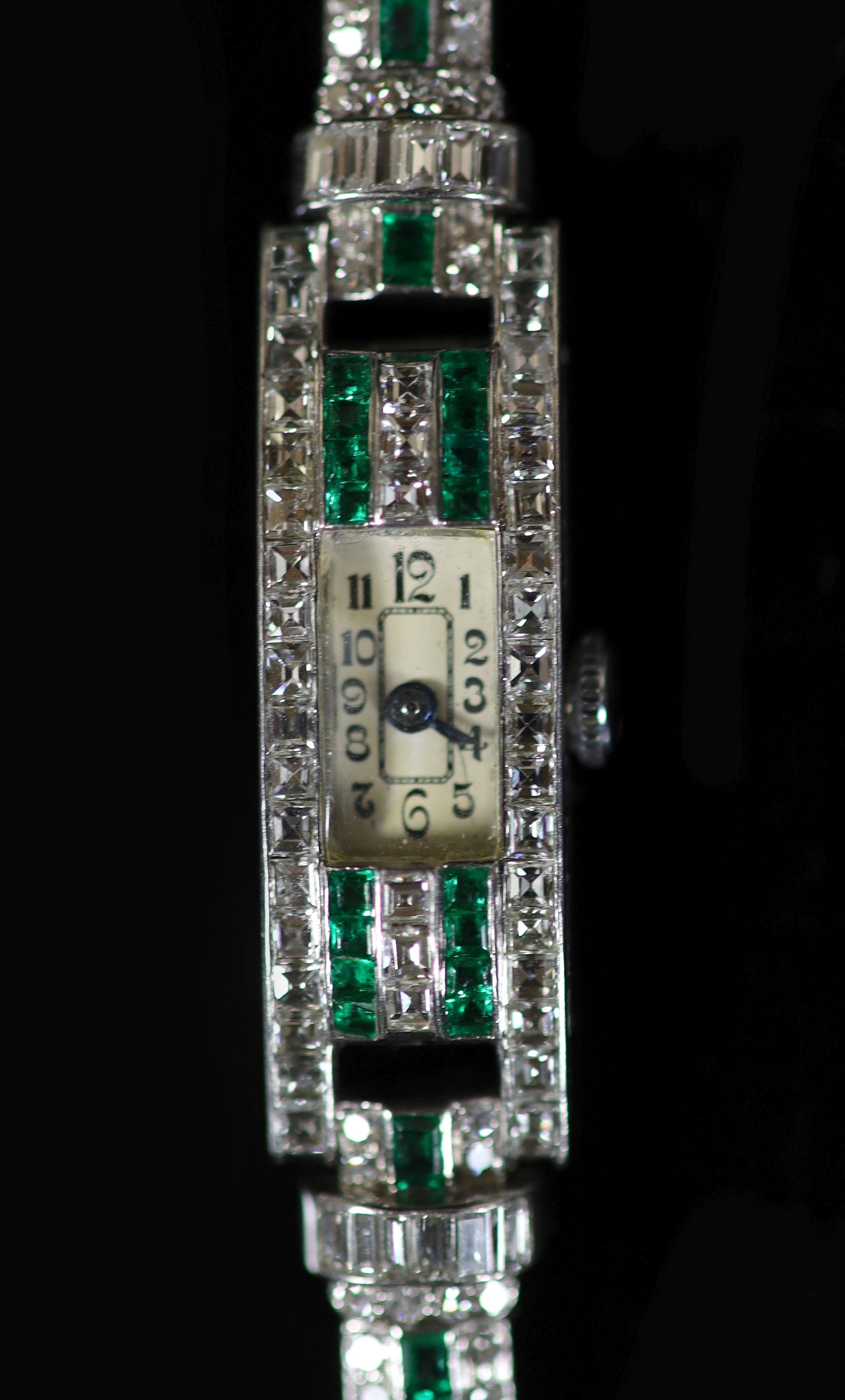 A lady's 1940's/1950's engraved platinum, emerald and diamond set manual wind rectangular cocktail watch, on a 9ct white gold bracelet